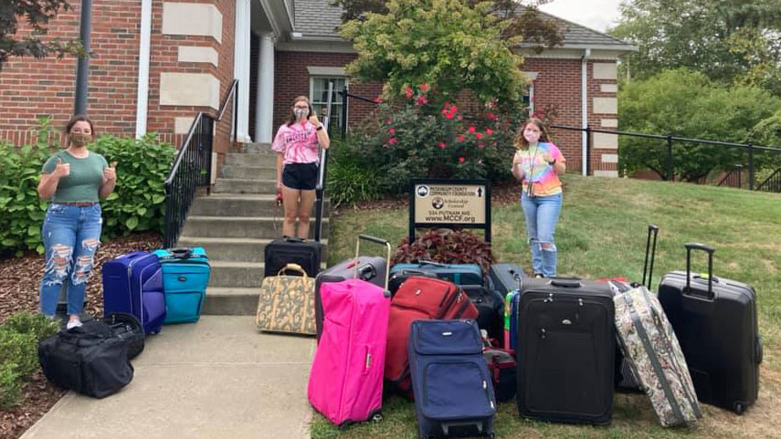 CYF members Amy McNutt Rachelle Snyder and Tomi Starcher pose with the condensed piles of luggage collected for the first ever Luggage Drive